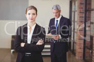Confident businesswoman with male colleague in background