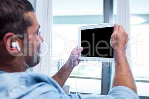 Young man listening to music while using tablet