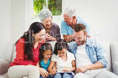 Smiling multi generation family using digital tablet