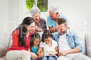 Smiling multi generation family using digital tablet