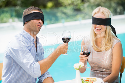 Blindfolded couple holding red wine