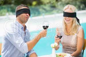 Blindfolded couple holding red wine
