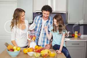 Smiling family preparing fruit juice