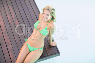 Portrait of beautiful woman in green bikini relaxing by pool sid