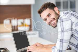 Portrait of happy young man using laptop