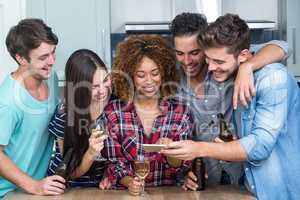 Friends looking in mobile phone while standing by table