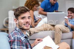 Young man with book while friends in background