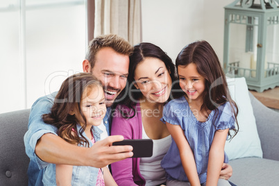 Family smiling while taking selfie on mobile phone