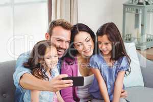 Family smiling while taking selfie on mobile phone