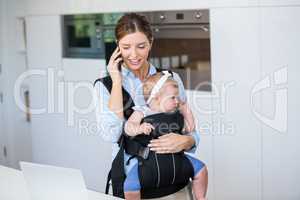 Woman talking on mobile phone while carrying baby girl