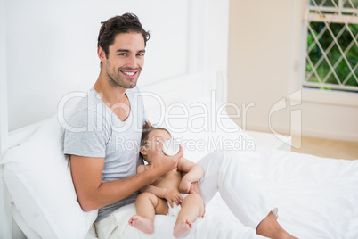 Happy man feeding milk to baby at home