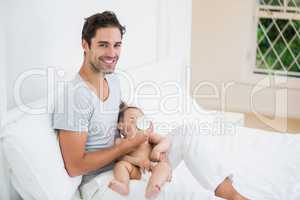 Happy man feeding milk to baby at home