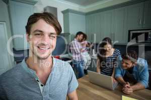 Portrait of happy man with friends in background at home