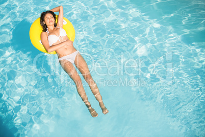 Beautiful woman in white bikini floating on inflatable tube in s