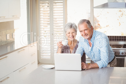 Portrait of senior couple with laptop in kitchen