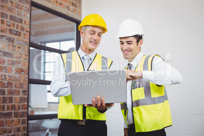 Smiling architects discussing while holding blueprint