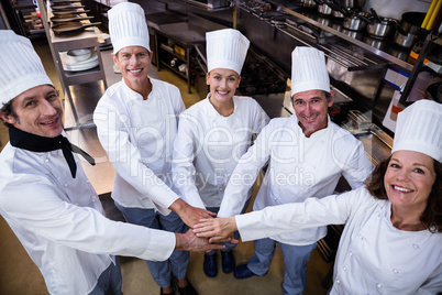 Portrait of chefs team putting hands together and cheering