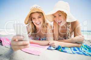 Two woman lying on the beach and looking at mobile phone