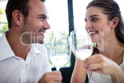 Couple toasting wine glasses at dining table