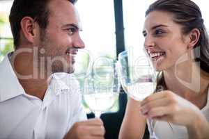 Couple toasting wine glasses at dining table
