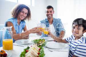 Portrait of family toasting glasses of orange juice while having