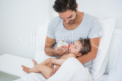 Man feeding milk to baby girl