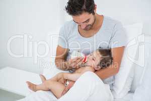 Man feeding milk to baby girl