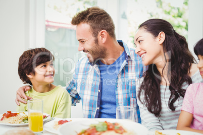 Smiling parents looking at son at dining table