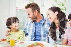 Smiling parents looking at son at dining table