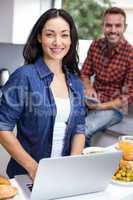 Young woman using laptop and man using digital tablet