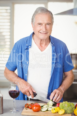 Portrait of senior man cutting vegetables