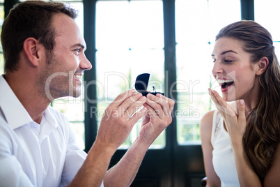 Man proposing to woman offering engagement ring