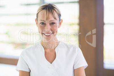 Happy female masseur standing at health spa