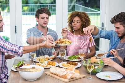 Multi-ethnic young friends having meal at table