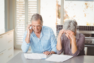 Worried senior couple with documents in kitchen
