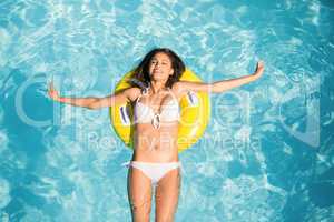 Beautiful woman in white bikini floating on inflatable tube in s