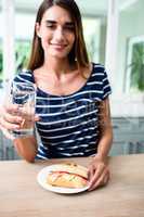 Portrait of smiling young woman with sandwich and drinking water