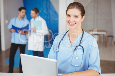 Portrait of happy female doctor with laptop