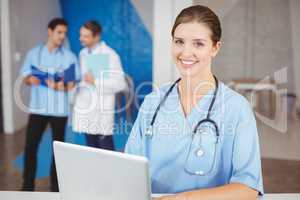 Portrait of happy female doctor with laptop