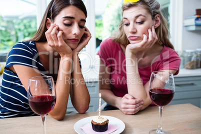 Unhappy friends sitting at table during birthday party