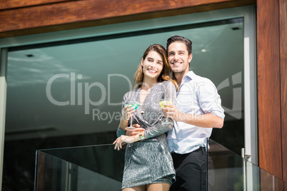 Couple with drinks standing in balcony