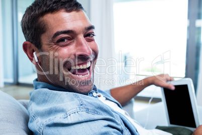 Portrait of young man listening to music while using tablet