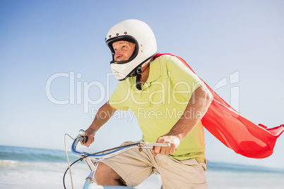 Senior superhero riding bike