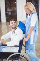Smiling doctor on wheelchair interacting with female colleague