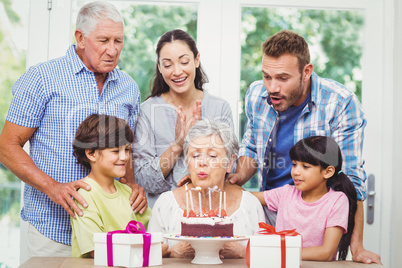 Granny blowing birthday candles with family
