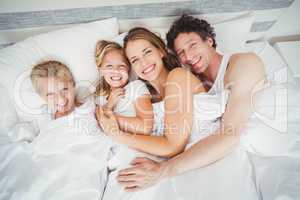 High angle view portrait of happy family relaxing on bed