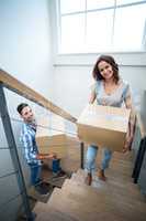 Portrait of cheerful couple holding cardboard boxes