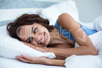 Portrait of happy woman lying on bed