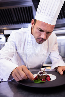 Male chef garnishing dessert plate