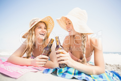 Happy women lying on the beach with beer bottle